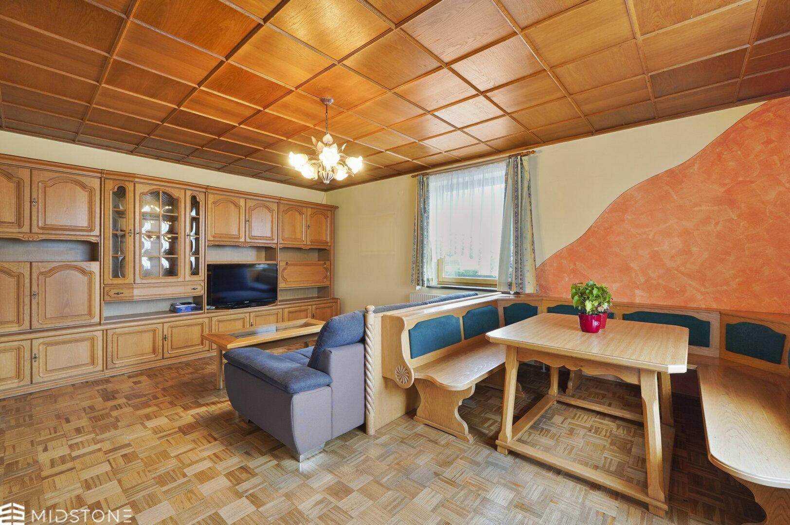 Rustikales Wohnzimmer mit Holztäfelung an der Decke und gemütlicher Sitzecke.