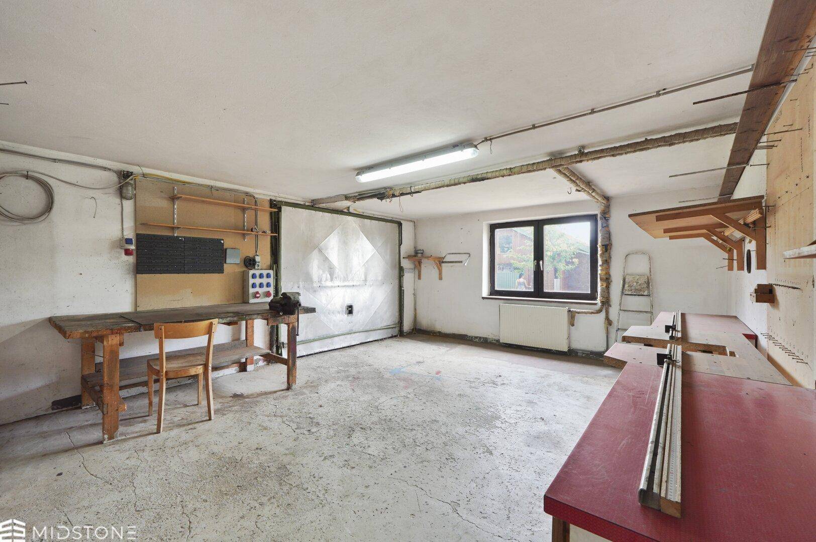 Geräumige Garage mit Werkbank und Fenster, ideal für Hobby und Lagerung.