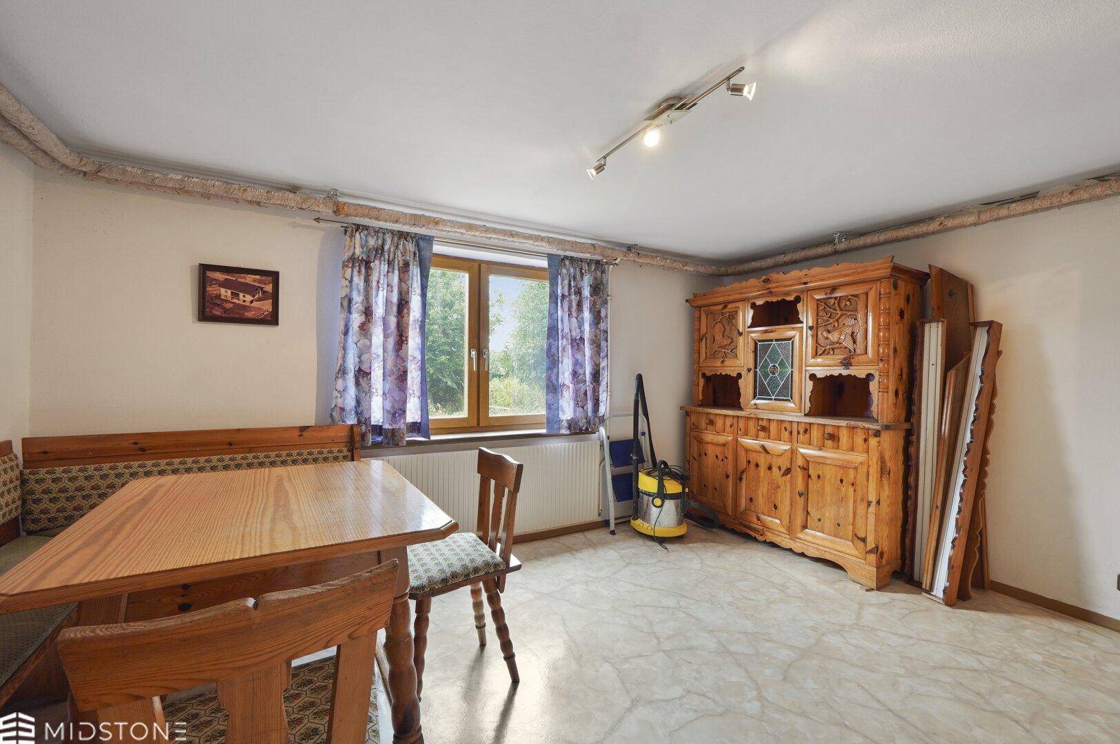 Gemütlicher Essbereich im Untergeschoss mit traditionellem Holzschrank und Fenster.