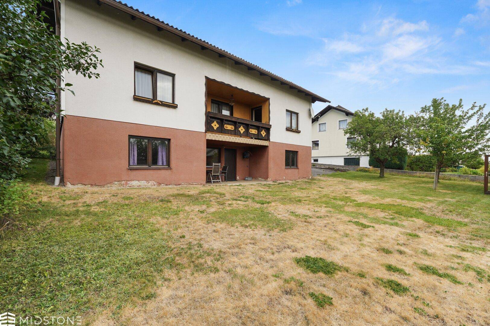 Hinterer Gartenbereich des Hauses mit Rasenfläche und Zugang zur Terrasse.