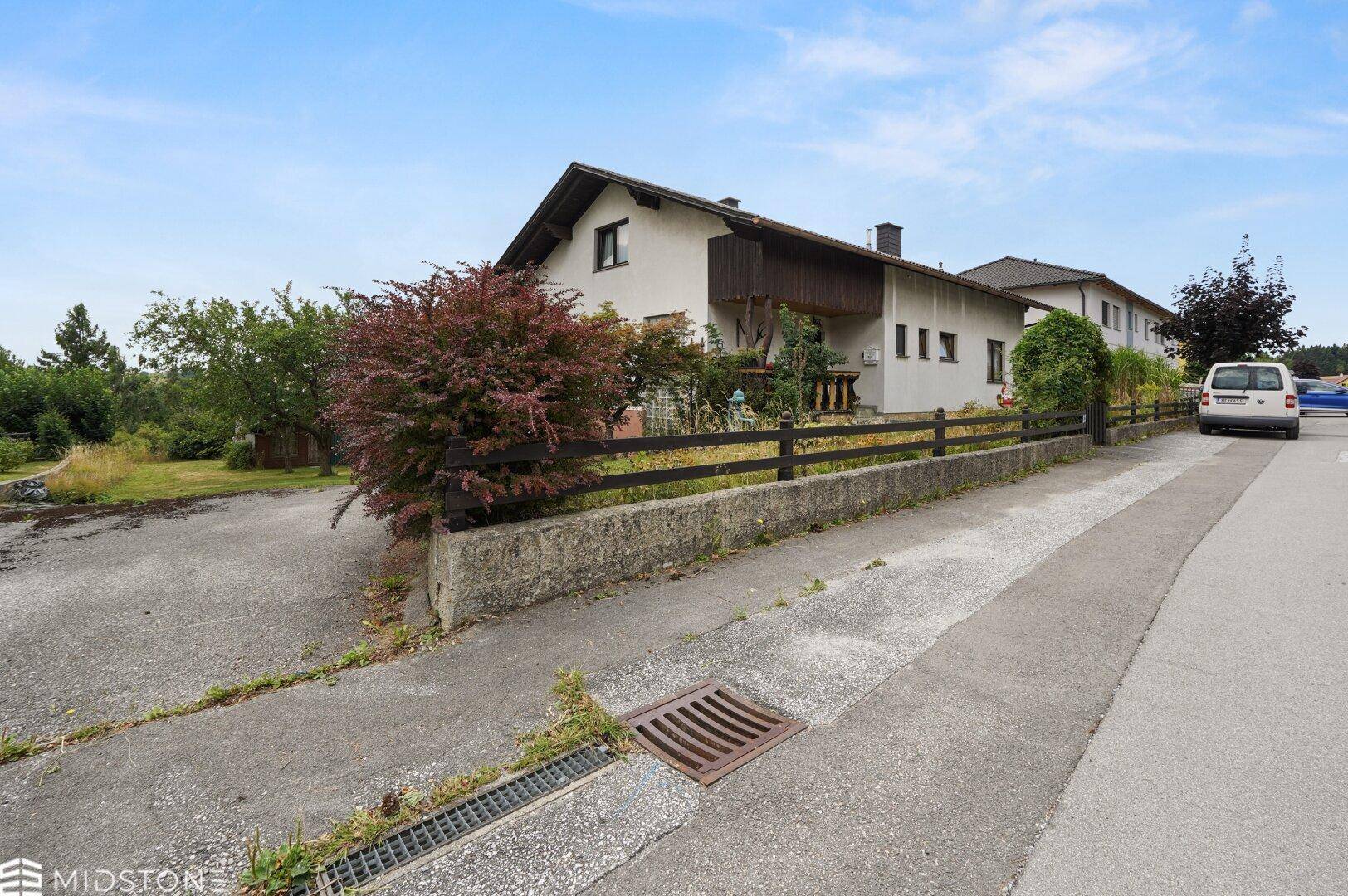 Einfamilienhaus von der Straße aus gesehen mit Vorgarten und Zufahrt.