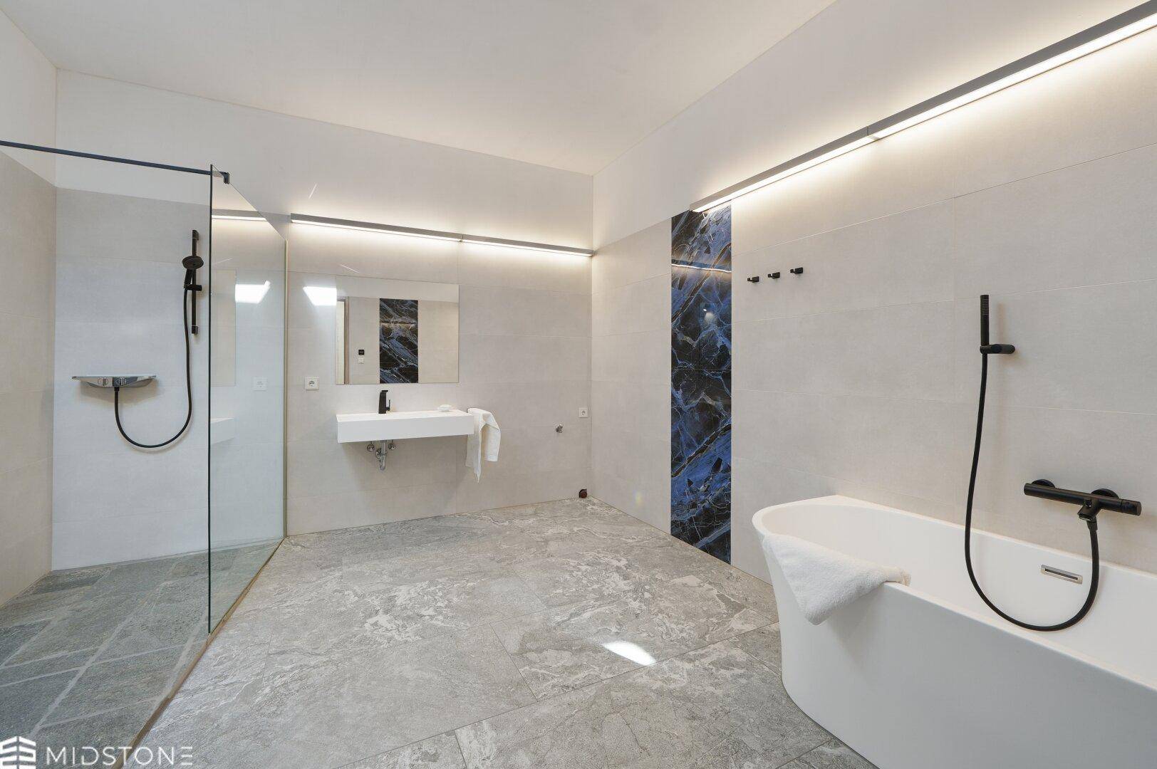 Modernes Badezimmer mit freistehender Badewanne, begehbarer Dusche und eleganten Fliesen.