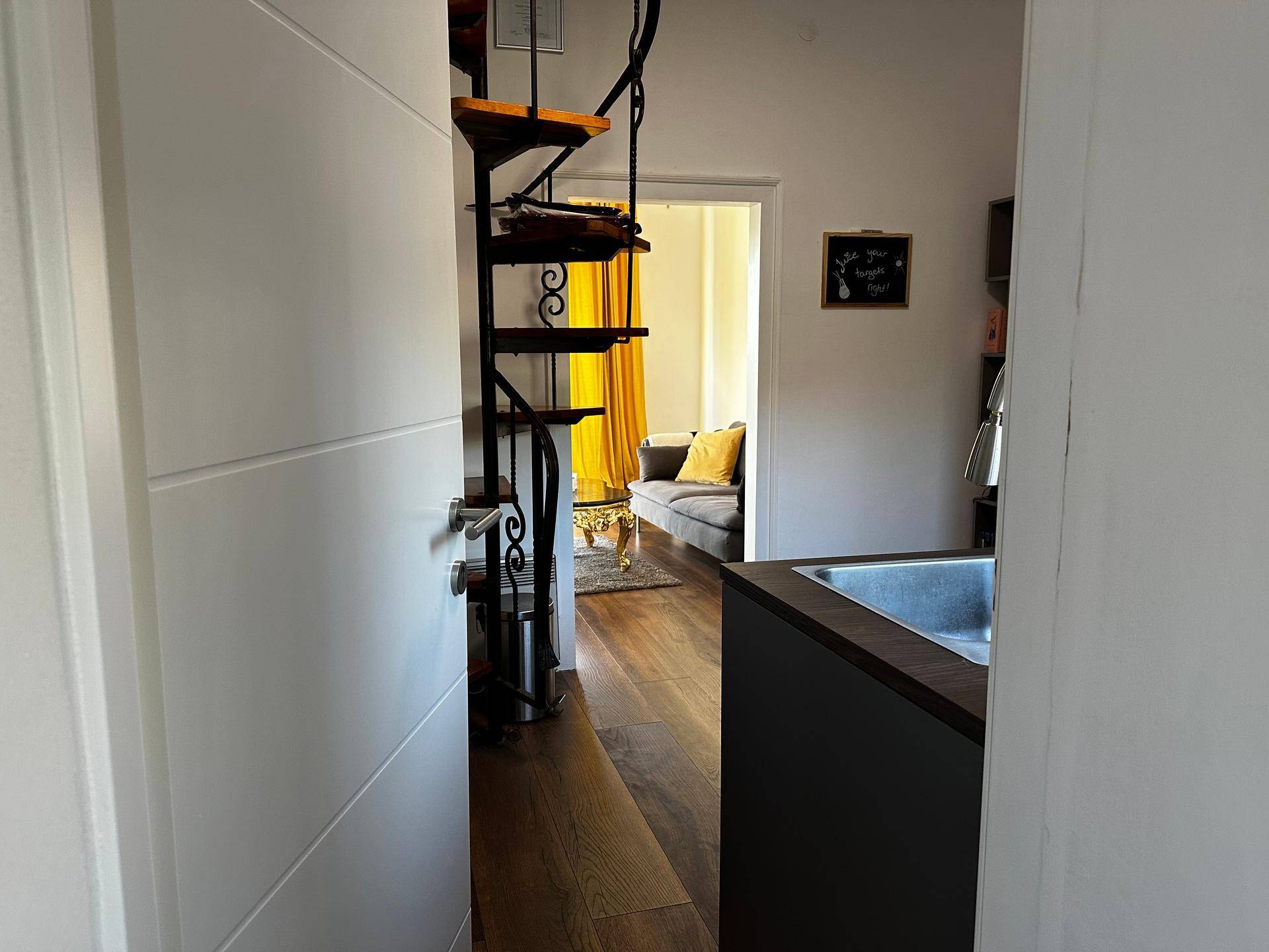 Heller Flur mit Wendeltreppe und Durchgang zum Wohnbereich.