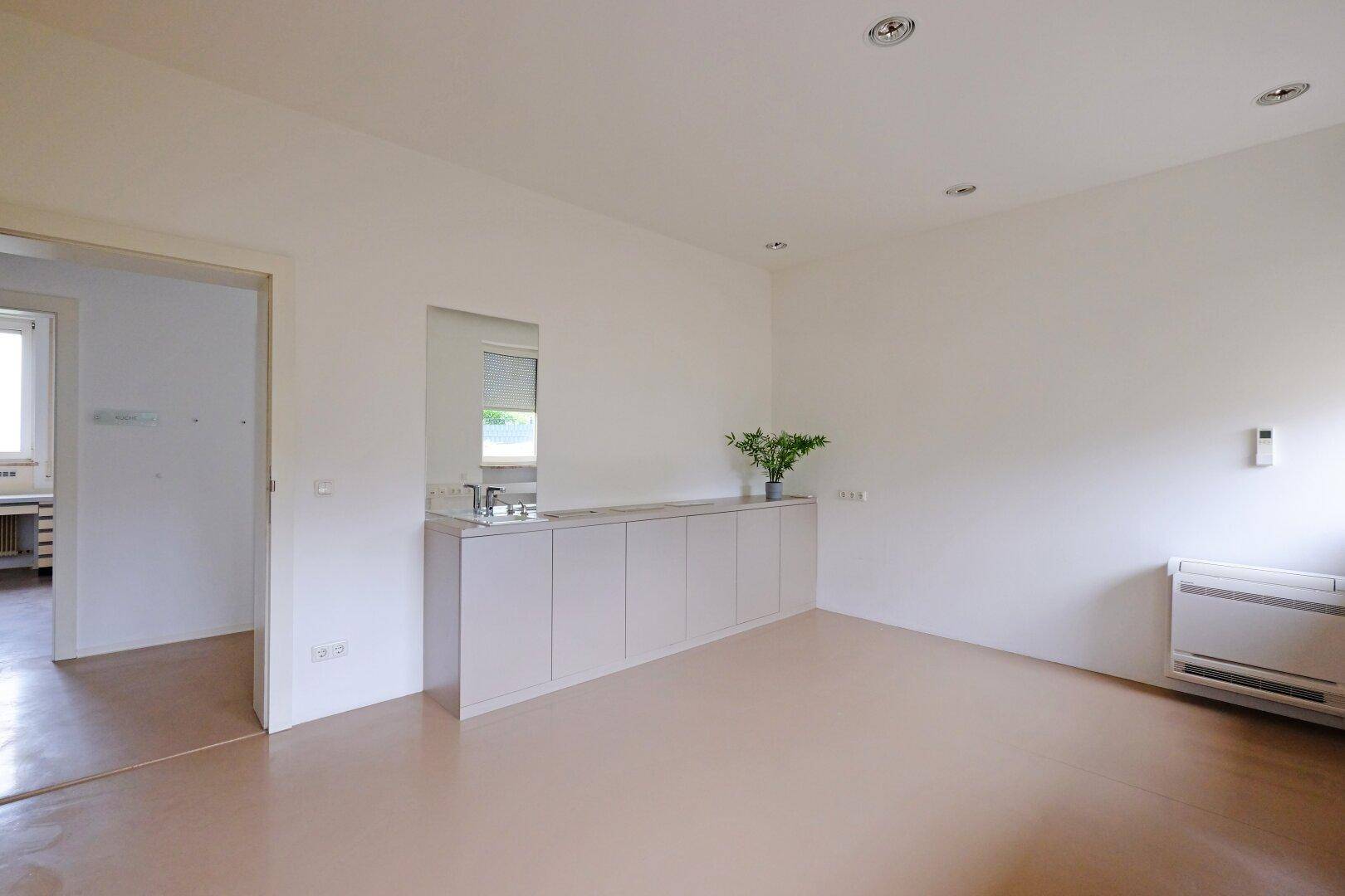 Geräumiges Büro mit Einbauschränken, Waschbecken und Zugang zu einem weiteren Raum.
