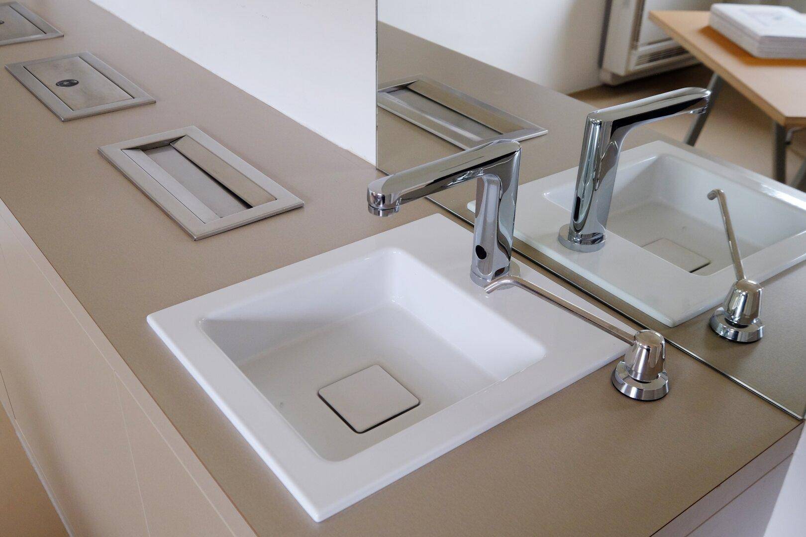 Detailaufnahme von zwei modernen Waschbecken mit Armaturen und integrierten Steckdosen.