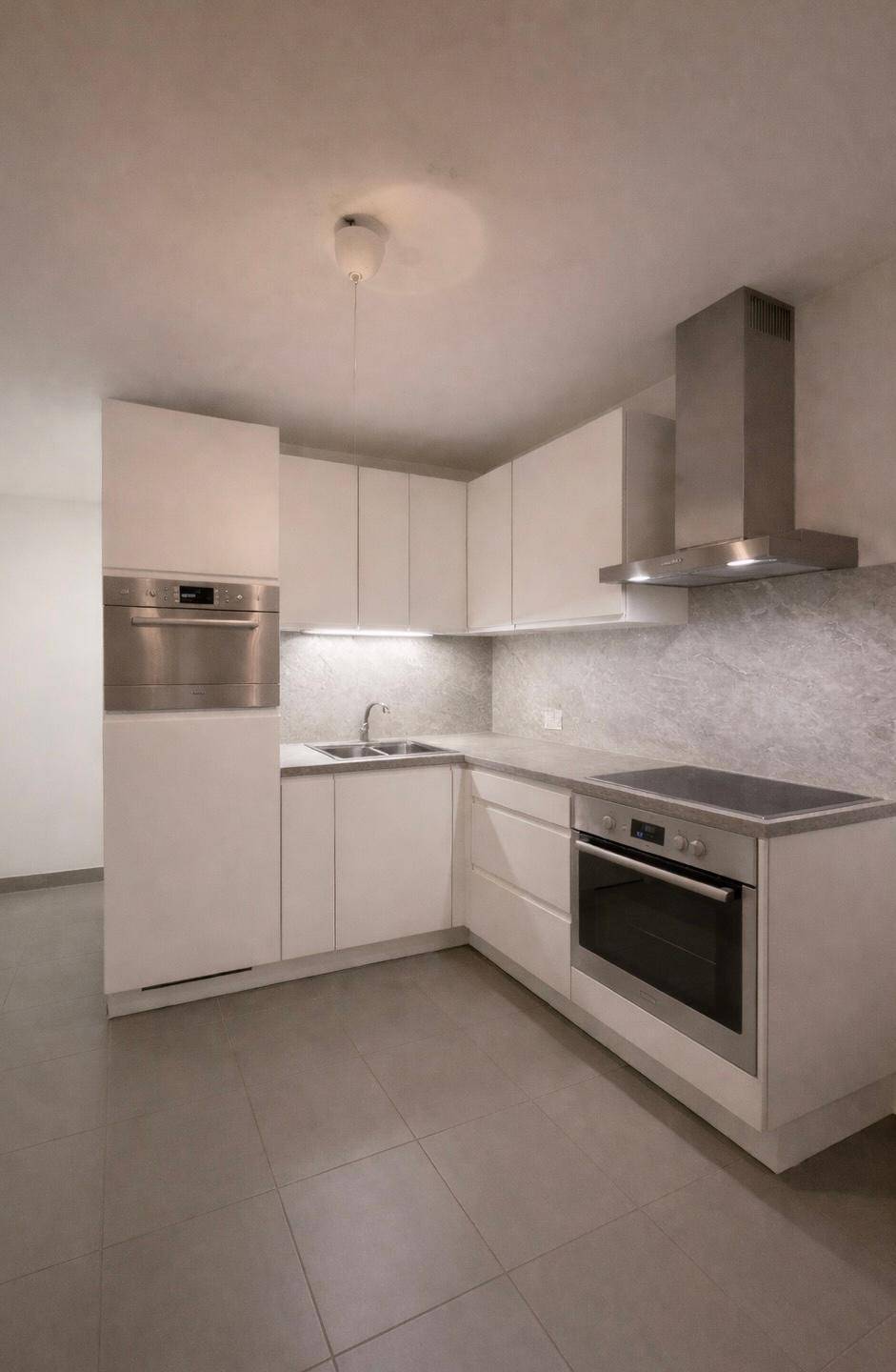 Moderne Einbauküche mit weißen Fronten, Induktionskochfeld und Dunstabzugshaube.
