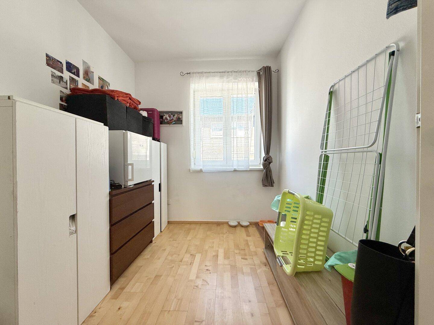 Helles Zimmer mit Holzboden und Fenster, vielseitig nutzbar als Schlaf- oder Gästezimmer.