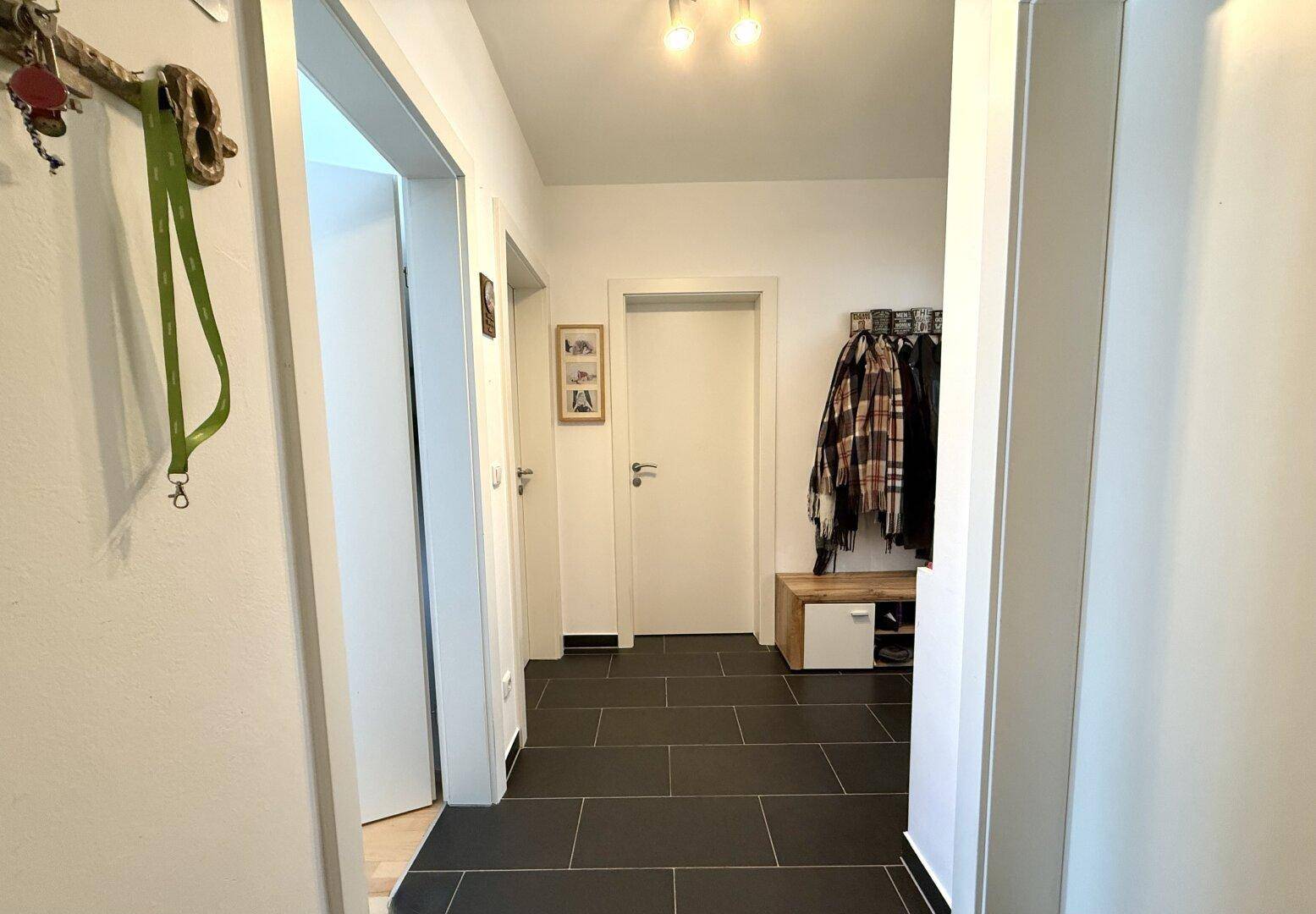 Eingangsbereich mit dunklen Fliesen, Garderobe und hellem Ambiente.