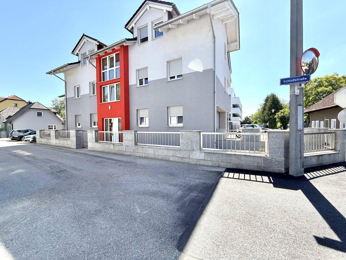 Moderne Wohnanlage mit ansprechender Fassadengestaltung in Grau und Rot an der Schloßstraße.