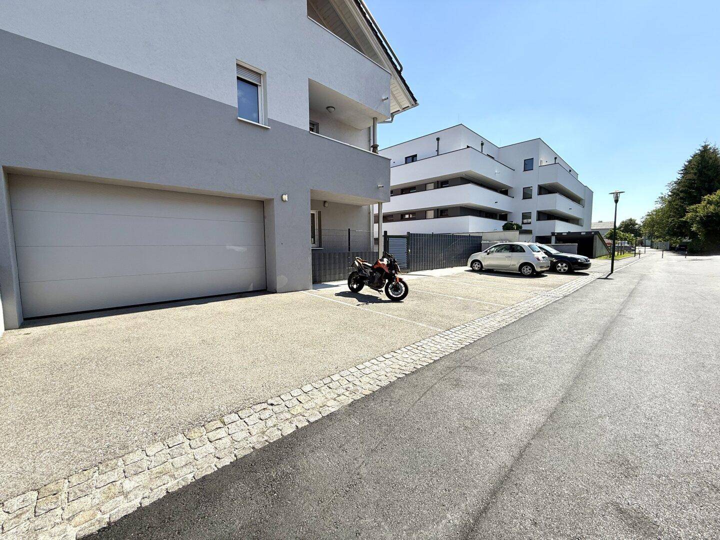 Garagenzufahrt und Außenstellplätze mit Blick auf die moderne Wohnbebauung.