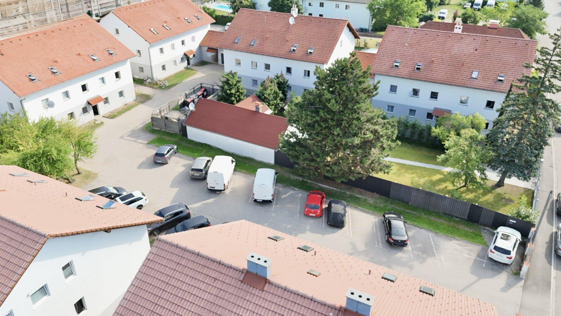 Luftaufnahme einer Wohnsiedlung mit mehreren Häusern, Parkplätzen und Grünflächen.