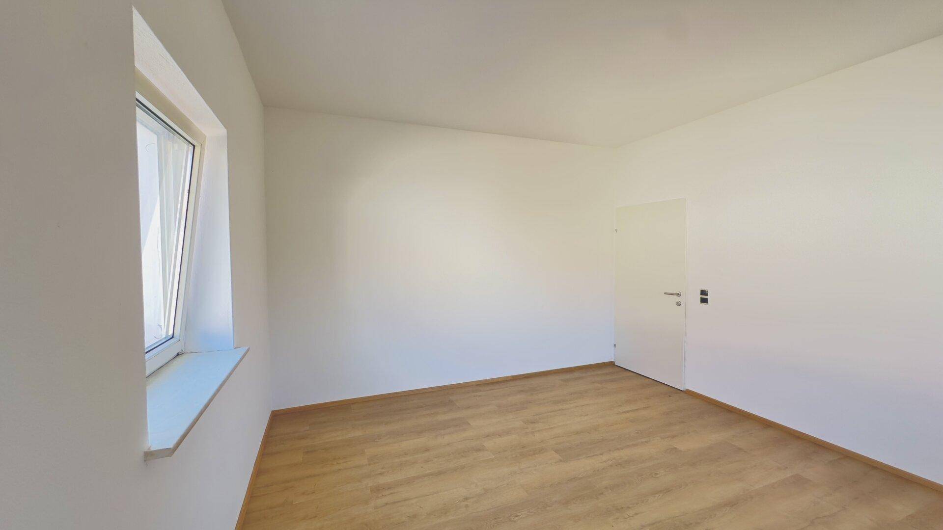 Detailansicht des Fensters in einem hellen, leeren Zimmer mit sauberem Laminatboden.
