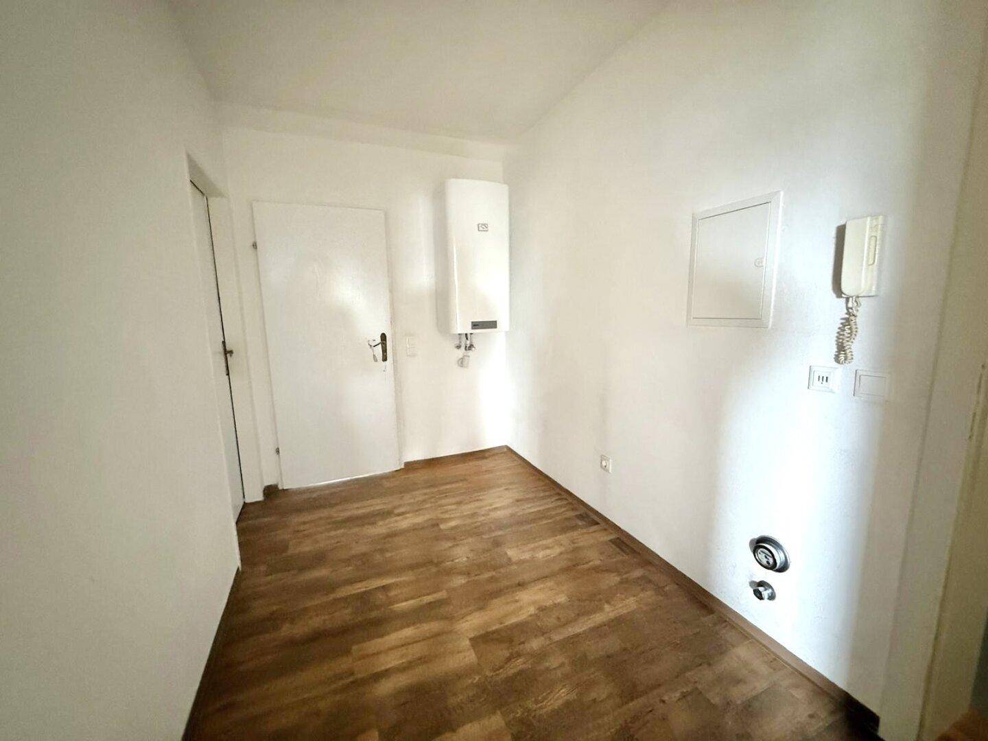 Eingangsbereich oder Flur mit Laminatboden, weißer Tür und Warmwasserbereiter.