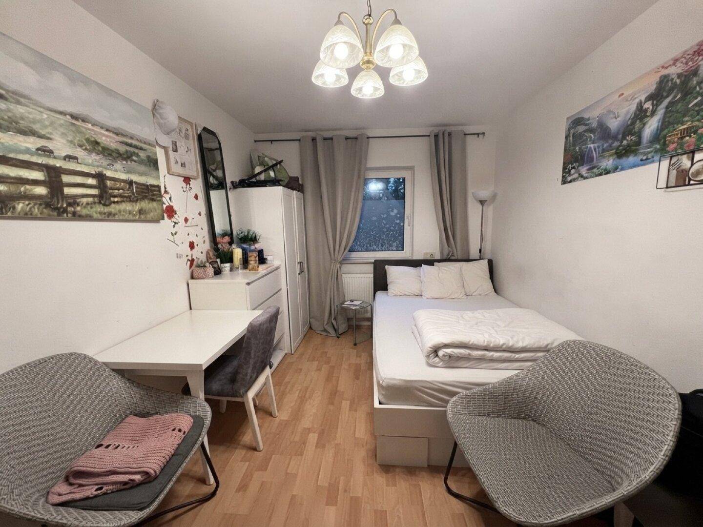 Gemütliches Schlafzimmer mit Einzelbett, Schreibtisch und Fenster, ausgestattet für eine Person.
