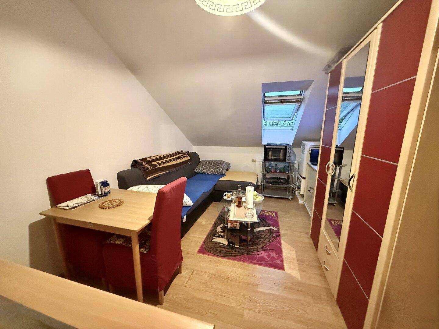 Wohn- und Schlafbereich im Dachgeschoss mit Dachfenster und Schrägen.