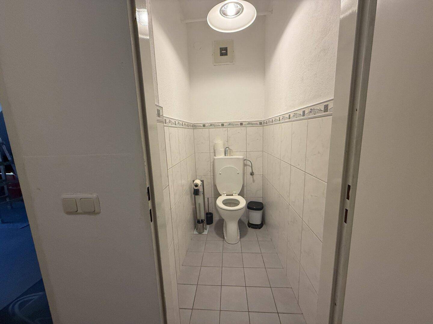 Kleines, gefliestes Gäste-WC mit Toilette und Spülkasten.