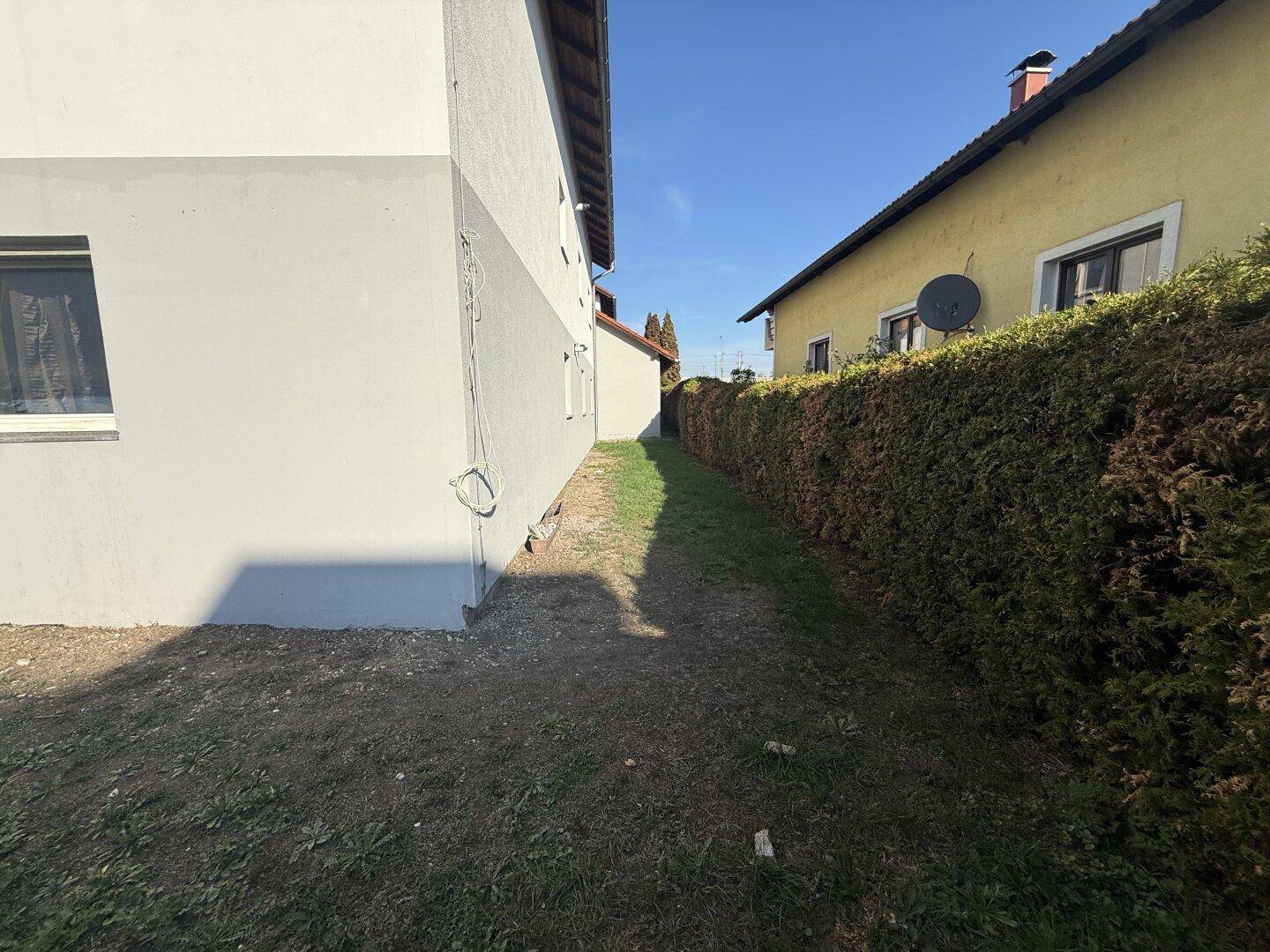 Seitenansicht des Hauses mit einer hohen Hecke, die Privatsphäre bietet.