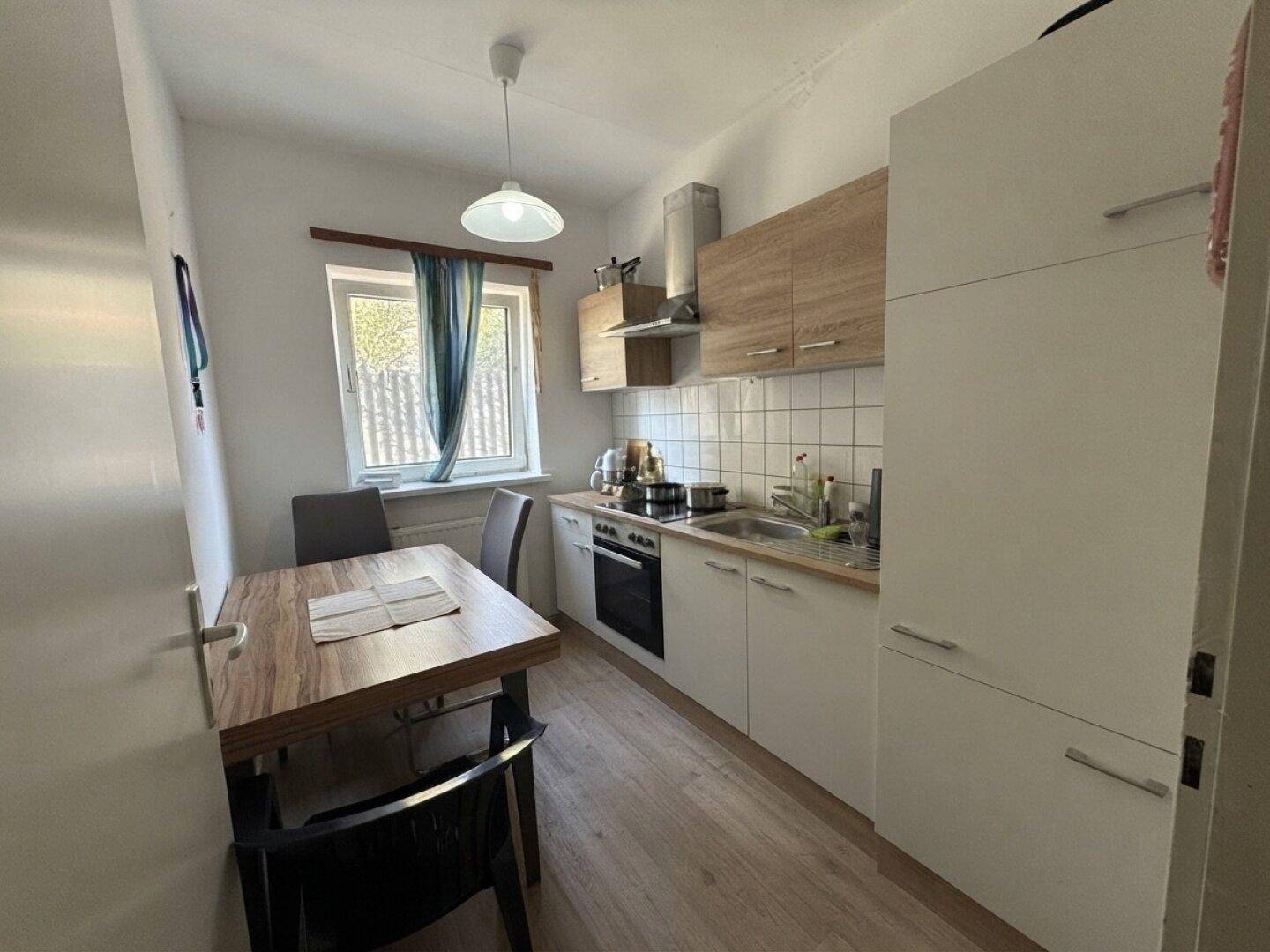 Funktionale Küche mit Einbauküche, Esstisch und Fenster mit Blick ins Grüne.