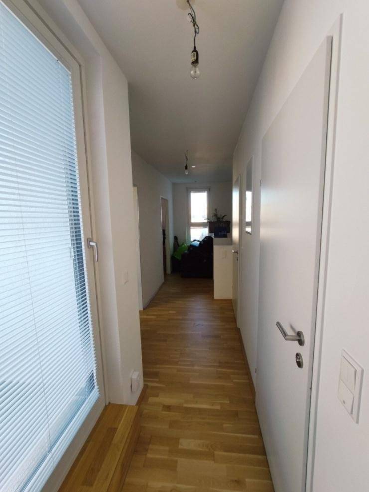 Langer, heller Flur mit Holzfußboden und Fenstern, die für natürliches Licht sorgen.