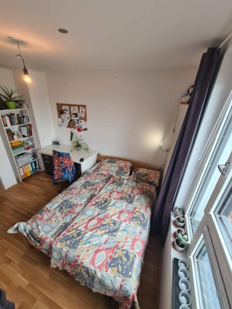Helles Schlafzimmer mit zwei Betten, Schreibtisch und Bücherregal, bietet viel natürliches Licht.