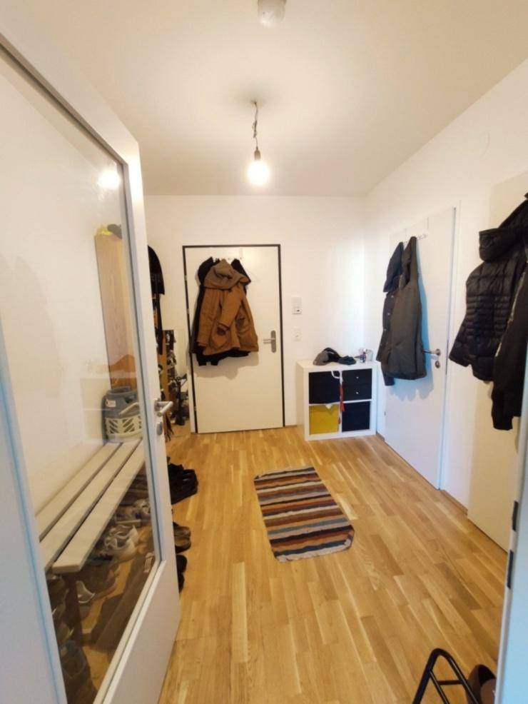 Heller Flur mit Garderobe, Schuhbank und Teppich, bietet praktischen Stauraum.