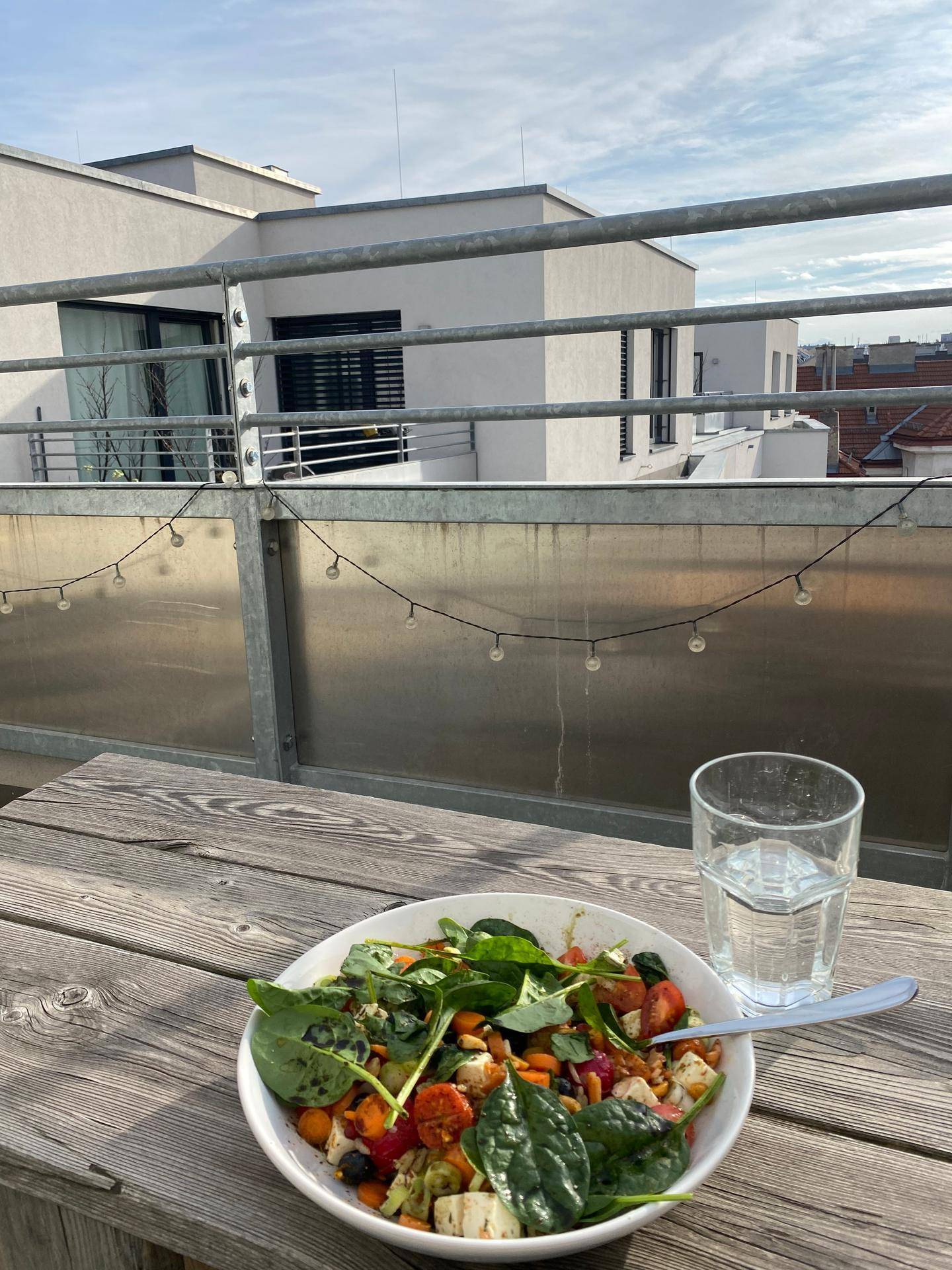 Sonniger Balkon mit Holztisch und Blick auf die umliegenden Gebäude, perfekt für Mahlzeiten im Freien.