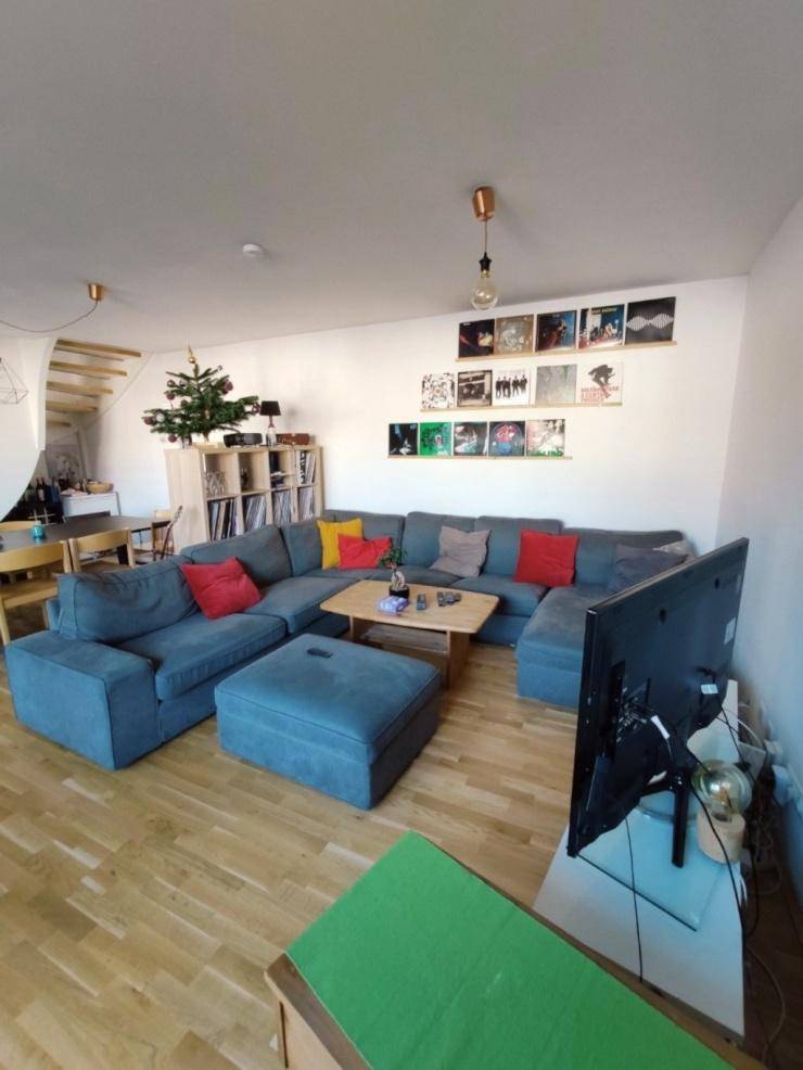 Geräumiger Wohnbereich mit großem Ecksofa, Fernseher und dekorativen Elementen an der Wand.