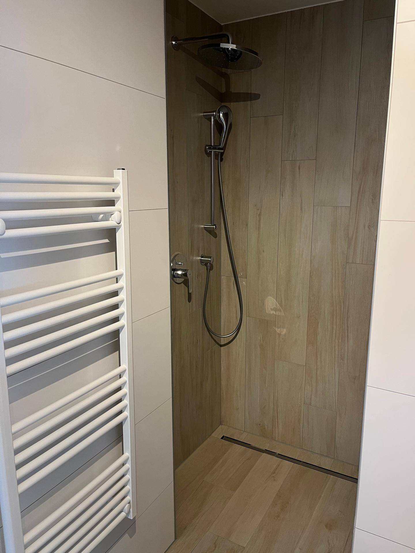 Moderne begehbare Dusche mit Regenduschkopf und beheiztem Handtuchhalter.