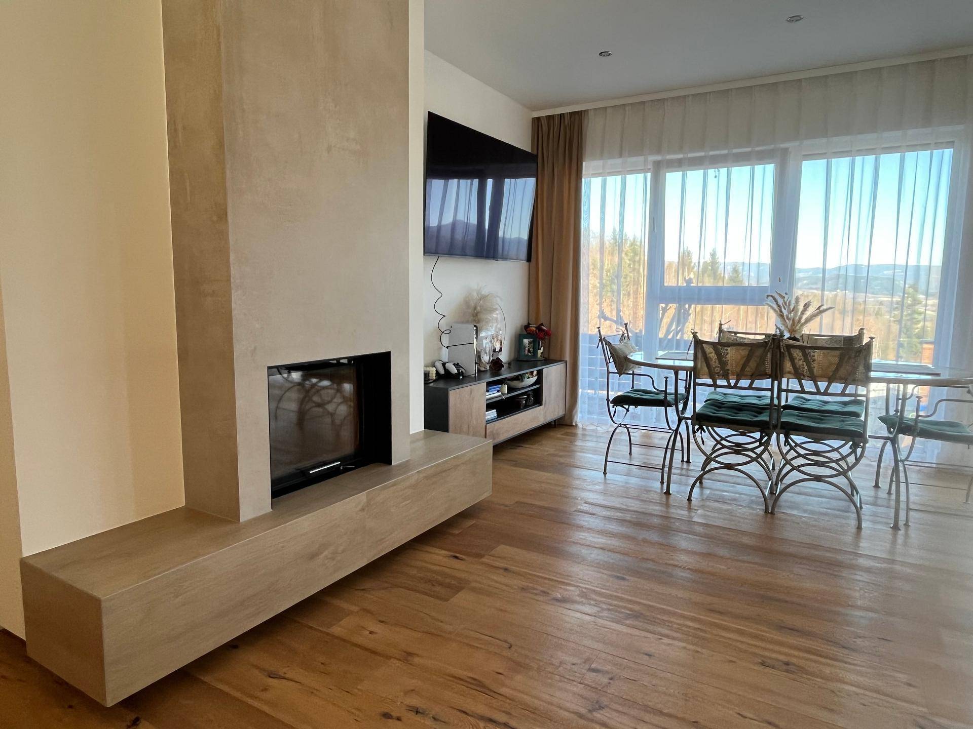 Heller Wohn- und Essbereich mit modernem Kamin, Holzboden und großen Fenstern.