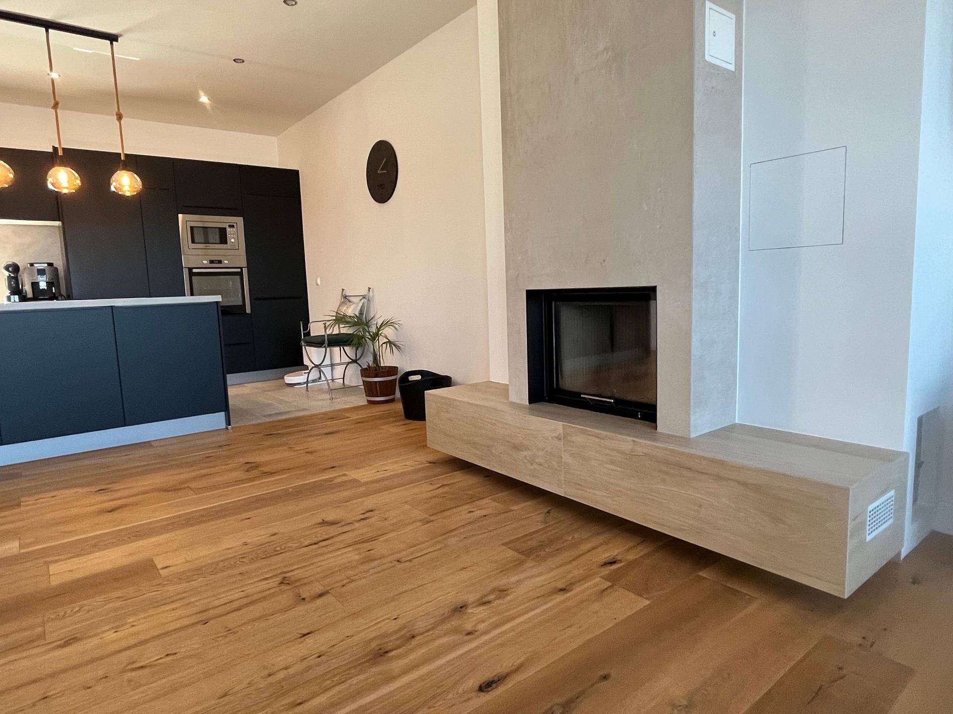Geräumiger Wohnbereich mit Holzboden und einem modernen Kamin als stilvolles, zentrales Element.