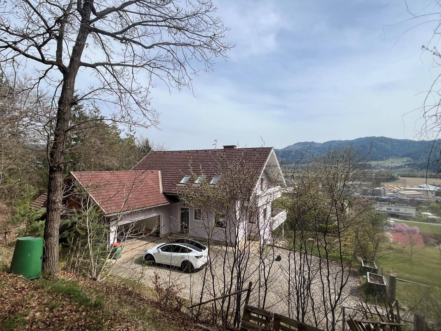 Haus in Hanglage mit weitem Blick über die Landschaft und umliegende Berge.