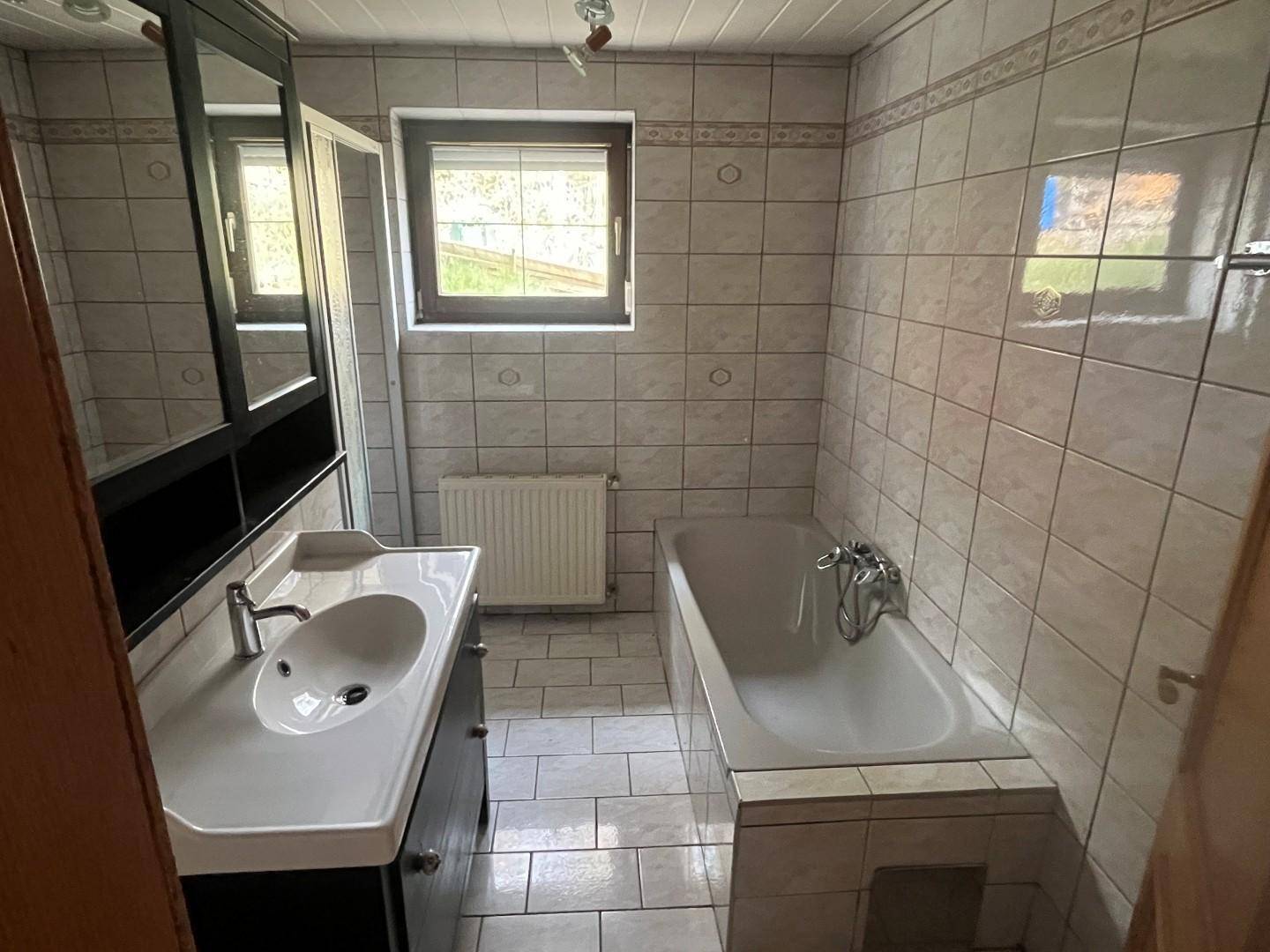 Badezimmer mit Badewanne, Waschbecken und Spiegelschrank über dem Waschtisch.