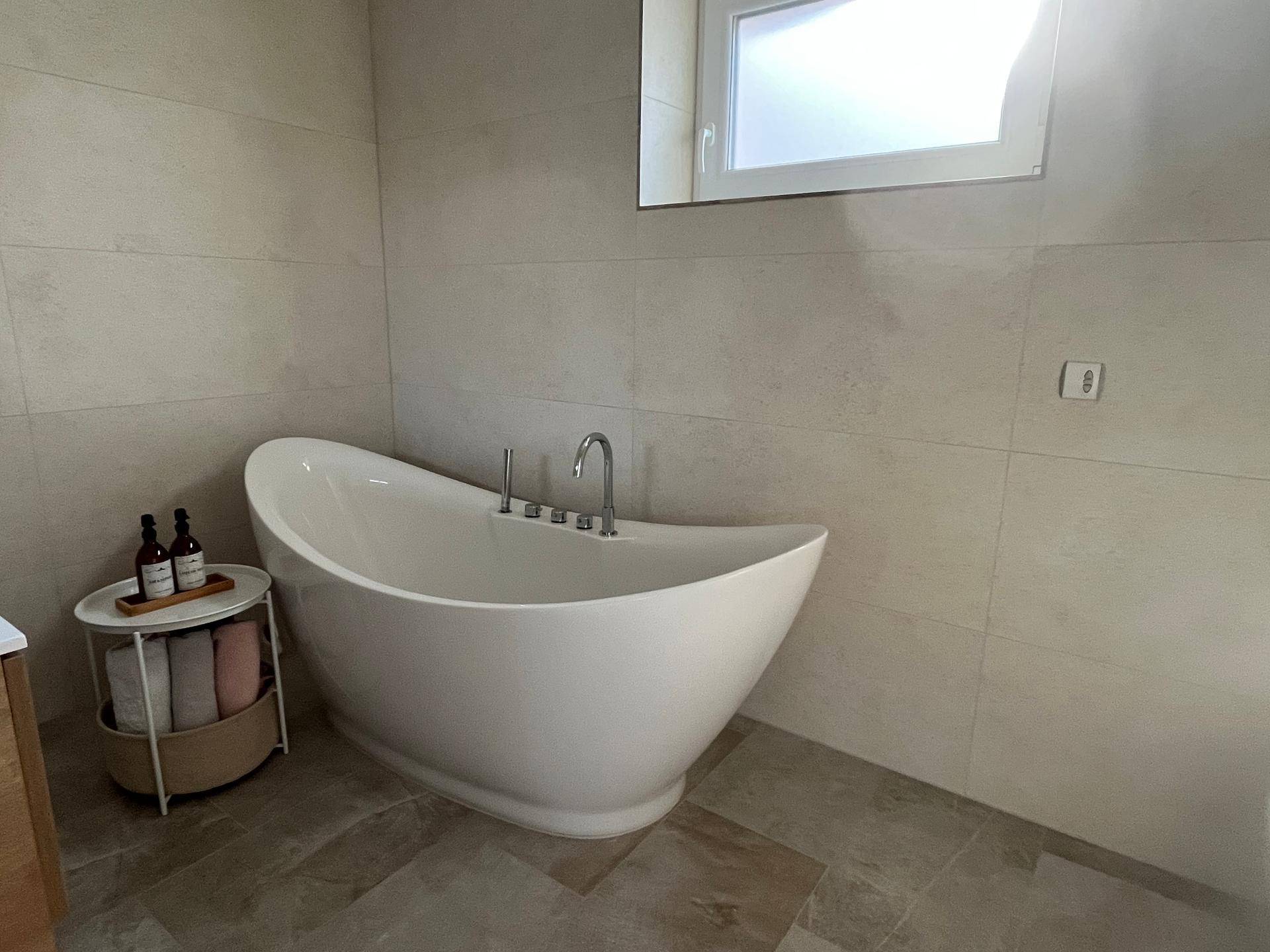 Modernes Badezimmer mit einer eleganten freistehenden Badewanne und großformatigen Fliesen.