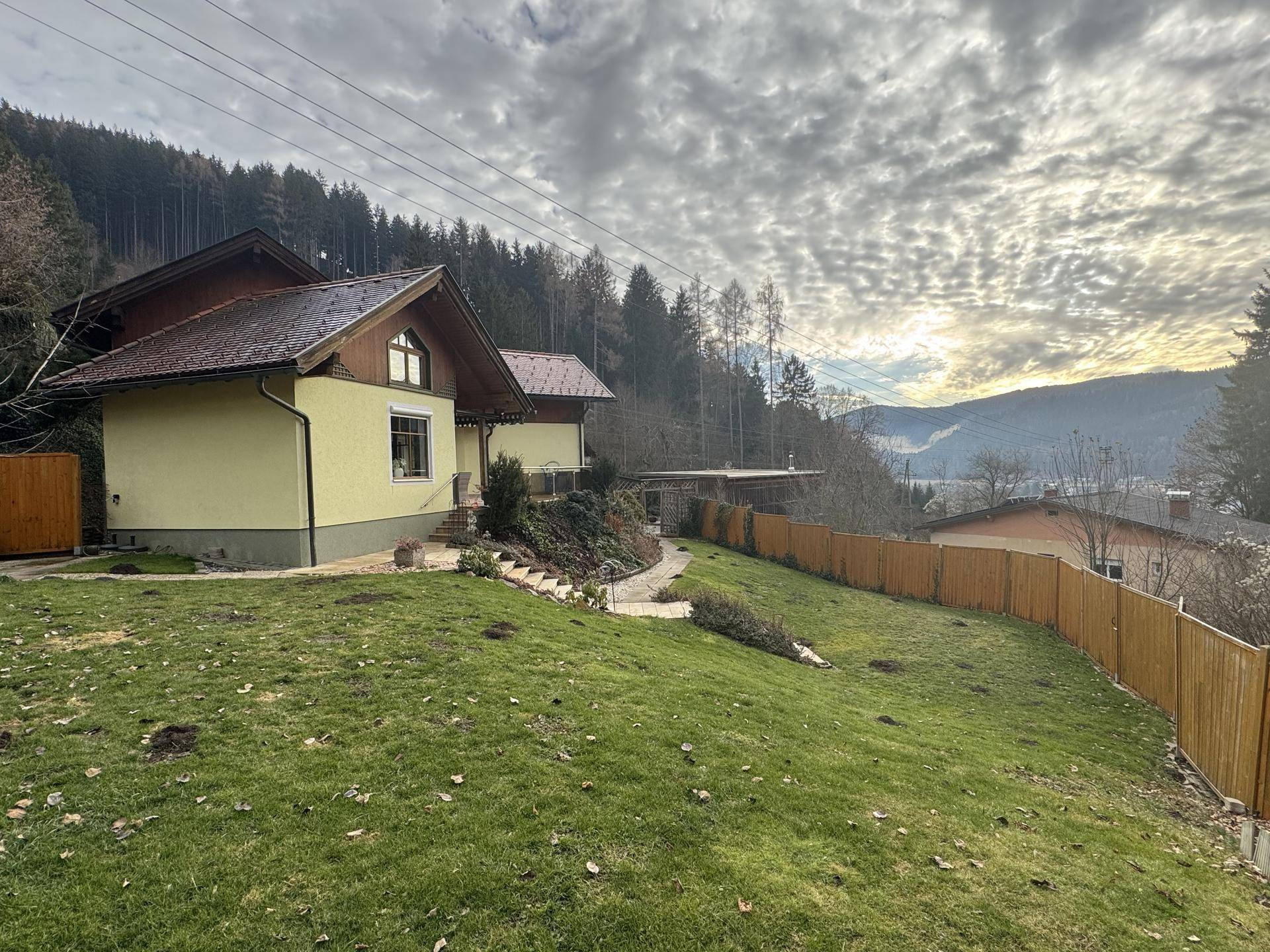 Panoramablick auf das Haus und die weite Landschaft mit Bergen und einem sonnigen Himmel.