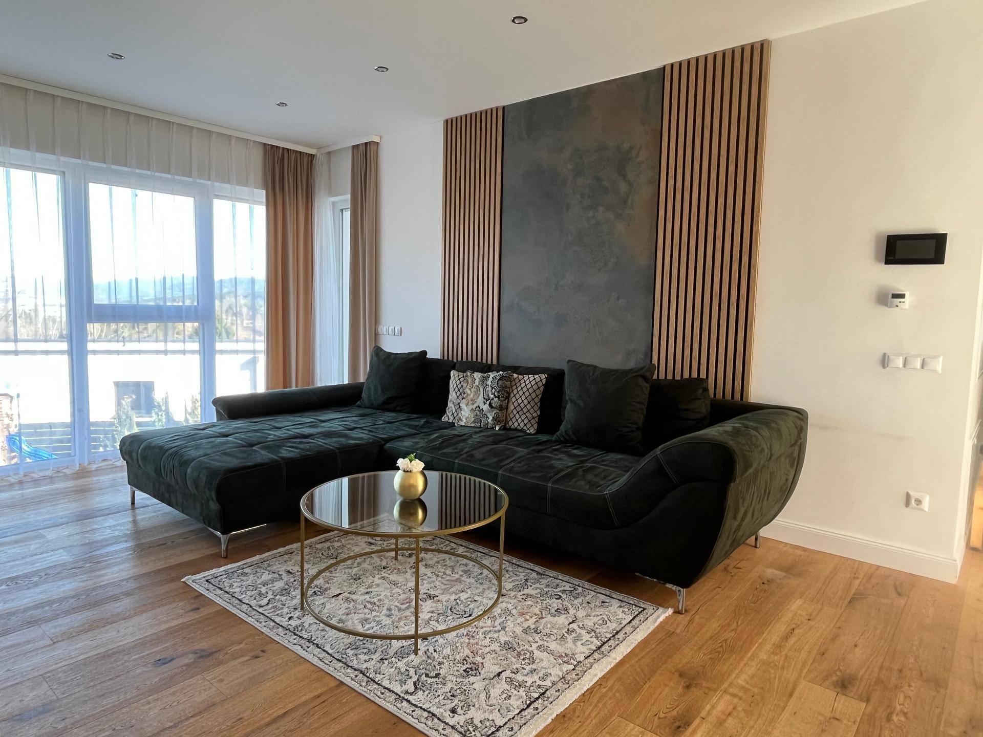 Gemütliches Wohnzimmer mit großem Ecksofa, Holzboden und dekorativer Wandgestaltung.