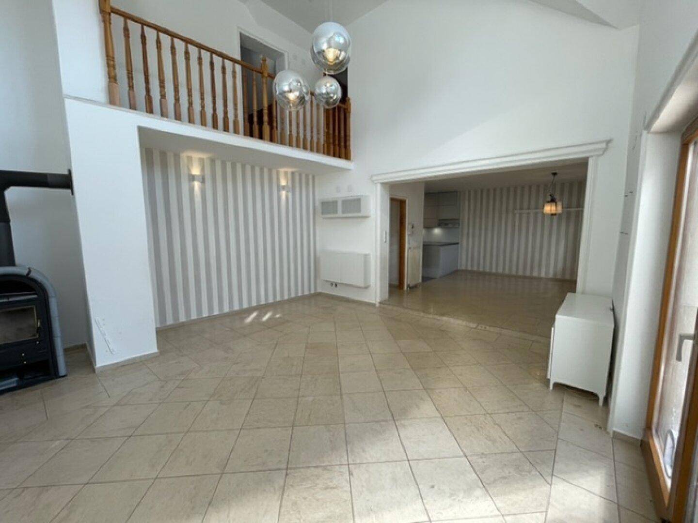 Geräumiger Wohnbereich mit Galerie, Kaminofen und gestreifter Akzentwand.