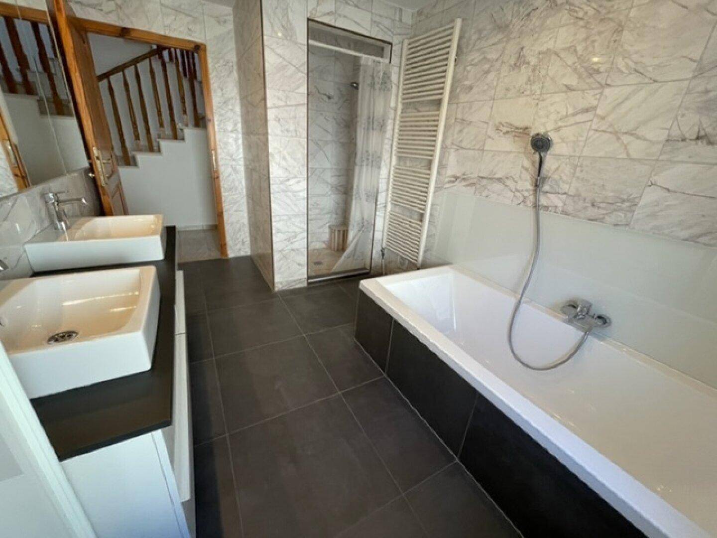 Modernes Badezimmer mit Doppelwaschbecken, Badewanne und separater Dusche.