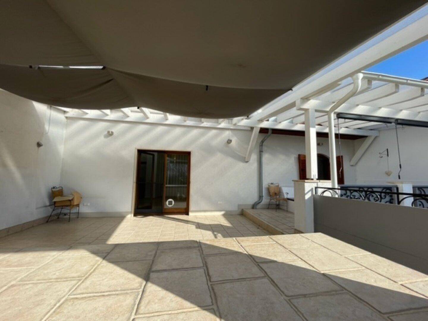 Große Sonnenterrasse mit Pergola, Sonnenschutz und Fliesenboden für Entspannung.