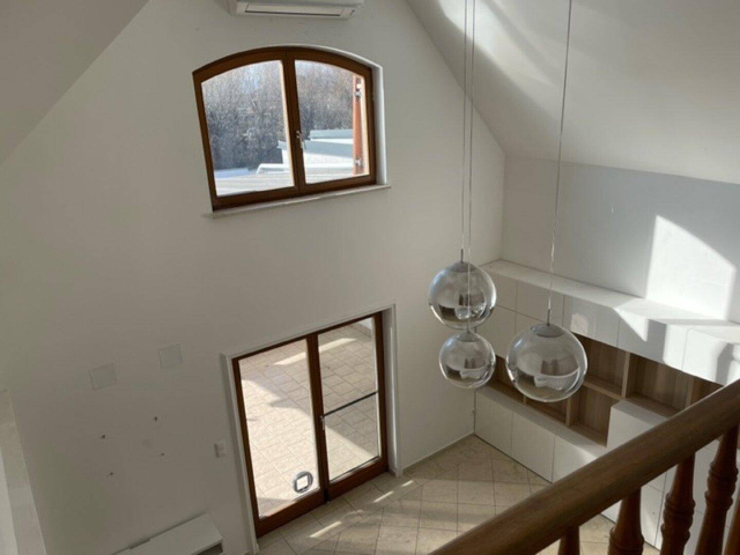 Blick von der Galerie in den lichtdurchfluteten Wohnbereich mit hohen Decken.