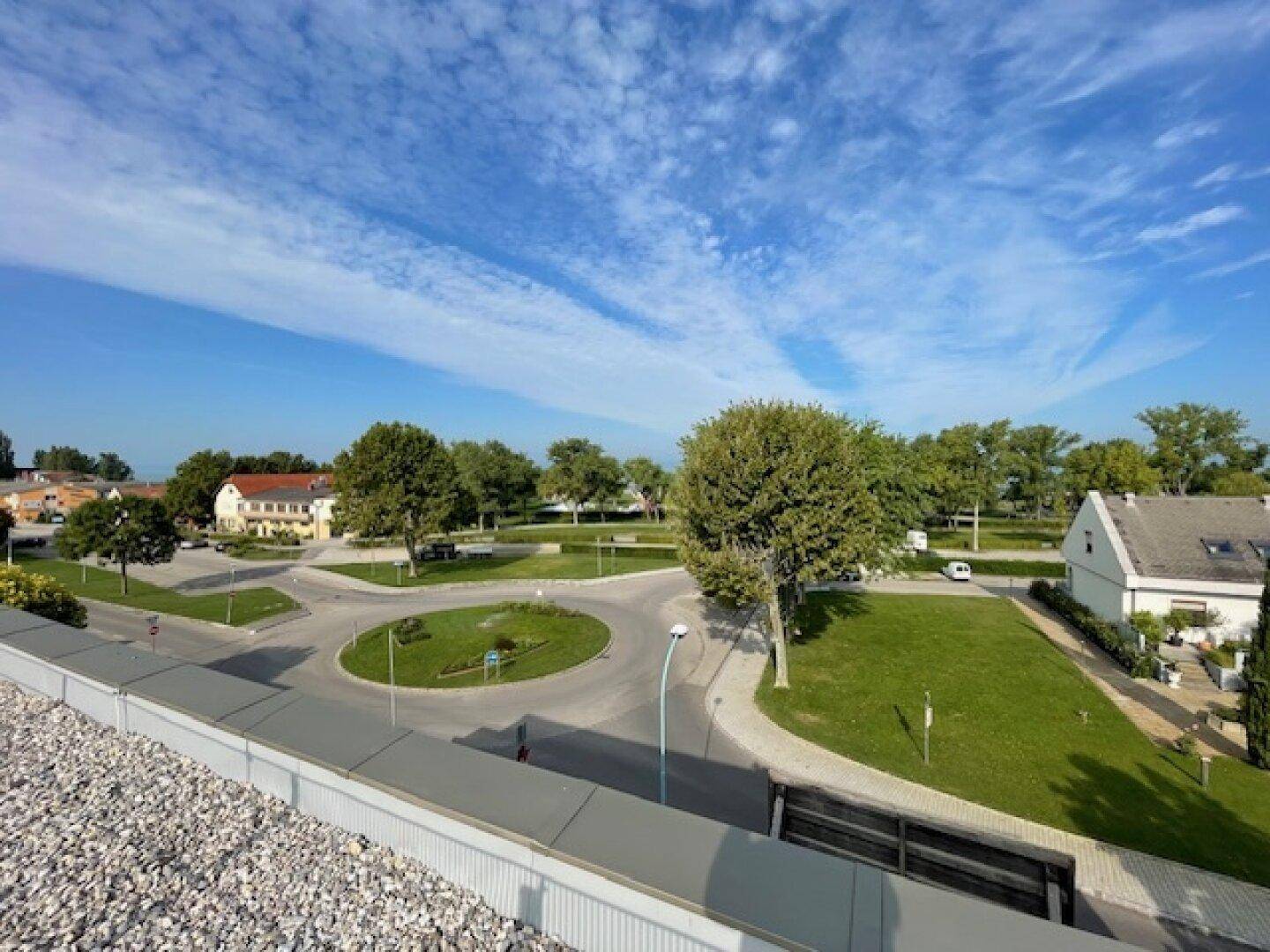 Weitblick von der Dachterrasse auf einen Kreisverkehr, Grünflächen und die umliegende Bebauung.