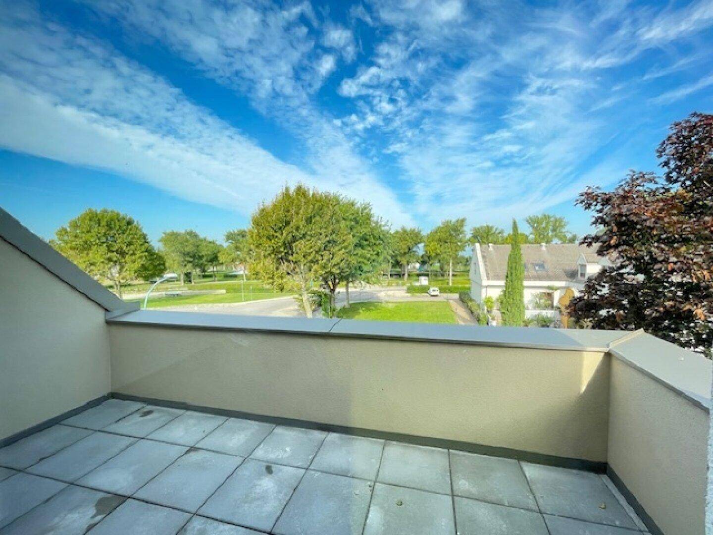 Balkon mit Fliesenboden und einem schönen Blick auf grüne Bäume und die Umgebung.
