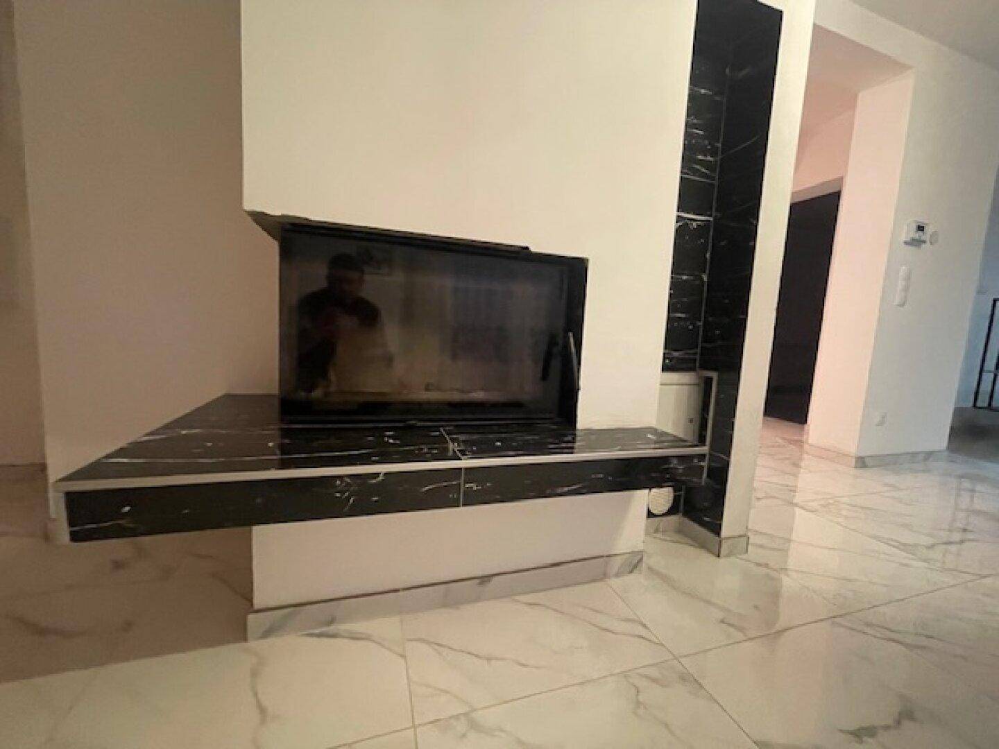 Moderner Kamin mit schwarzer Marmorplatte als stilvolles Element im Wohnbereich.
