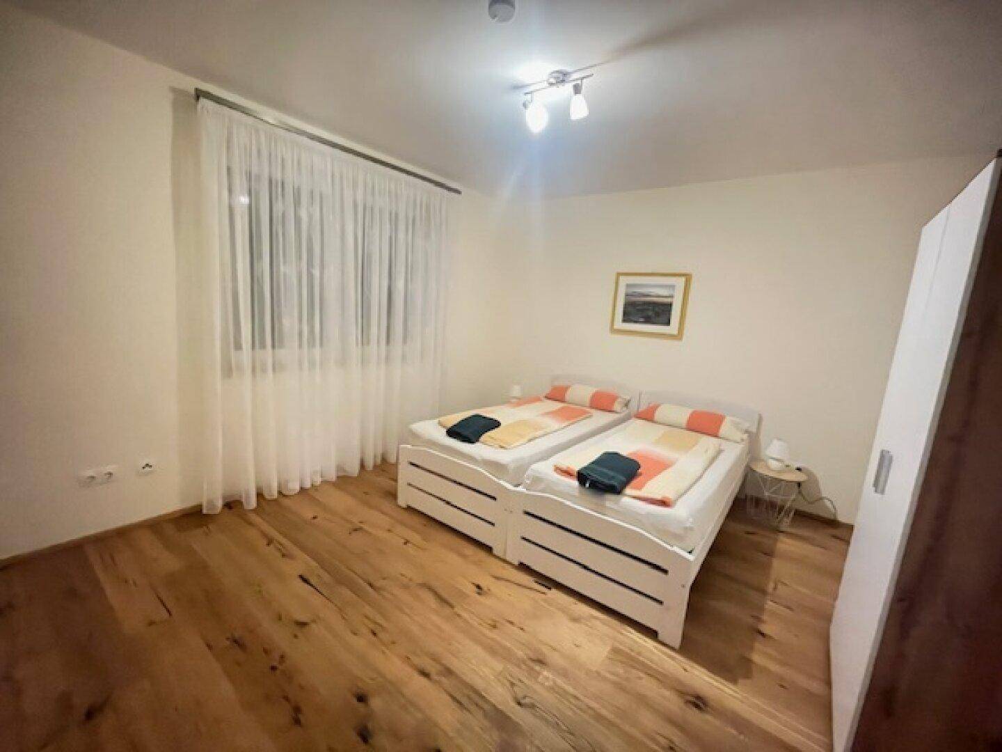 Gemütliches Schlafzimmer mit zwei Einzelbetten und warmem Holzparkettboden.