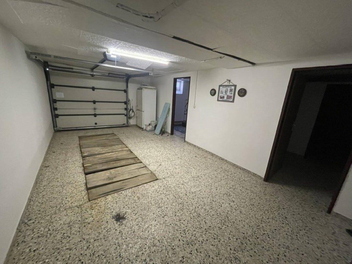 Geräumige Garage mit einem Rolltor und einem strapazierfähigen Betonboden.