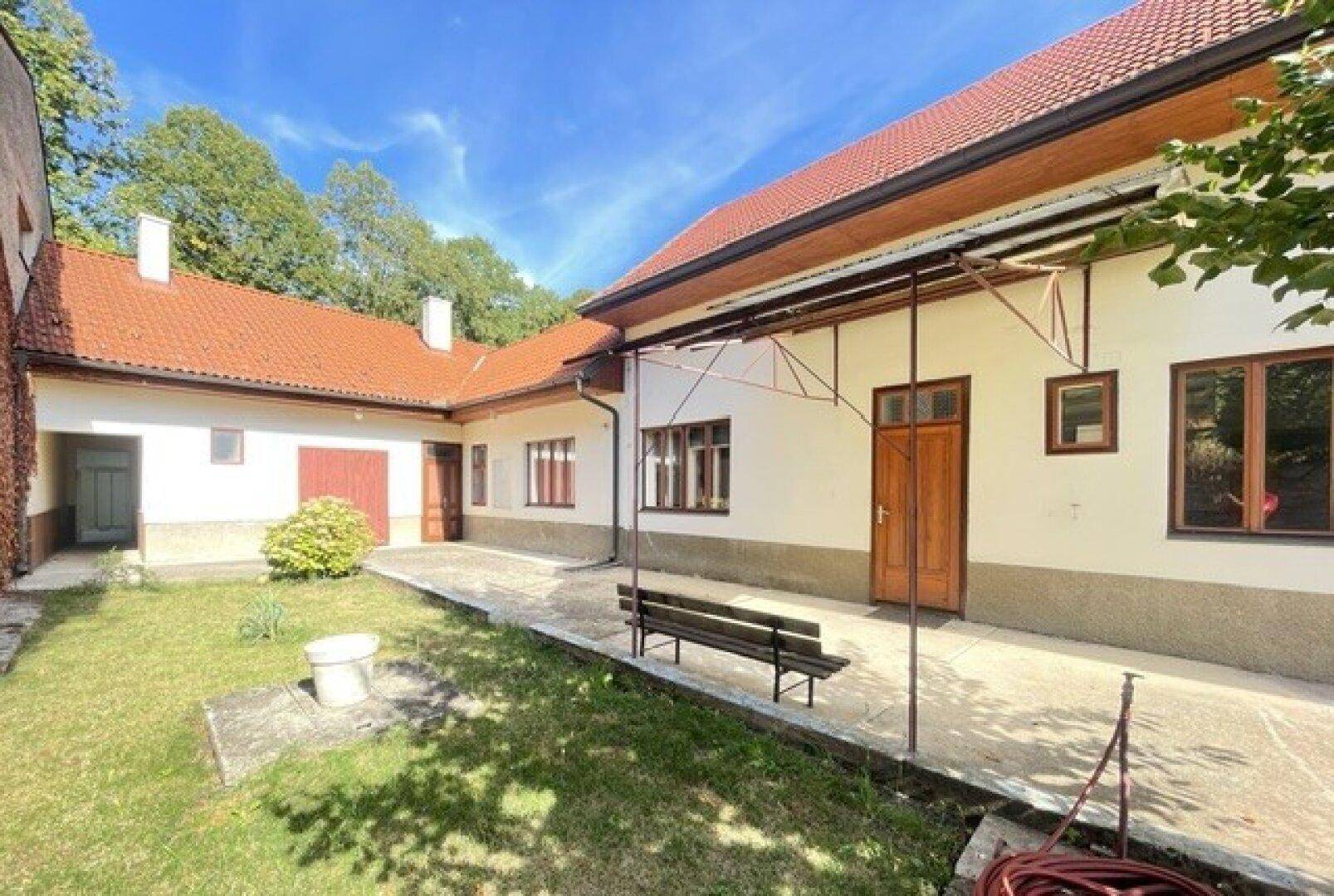 Innenhof des Hauses mit Sitzbank, gepflastertem Bereich und Blick auf das Gebäude.