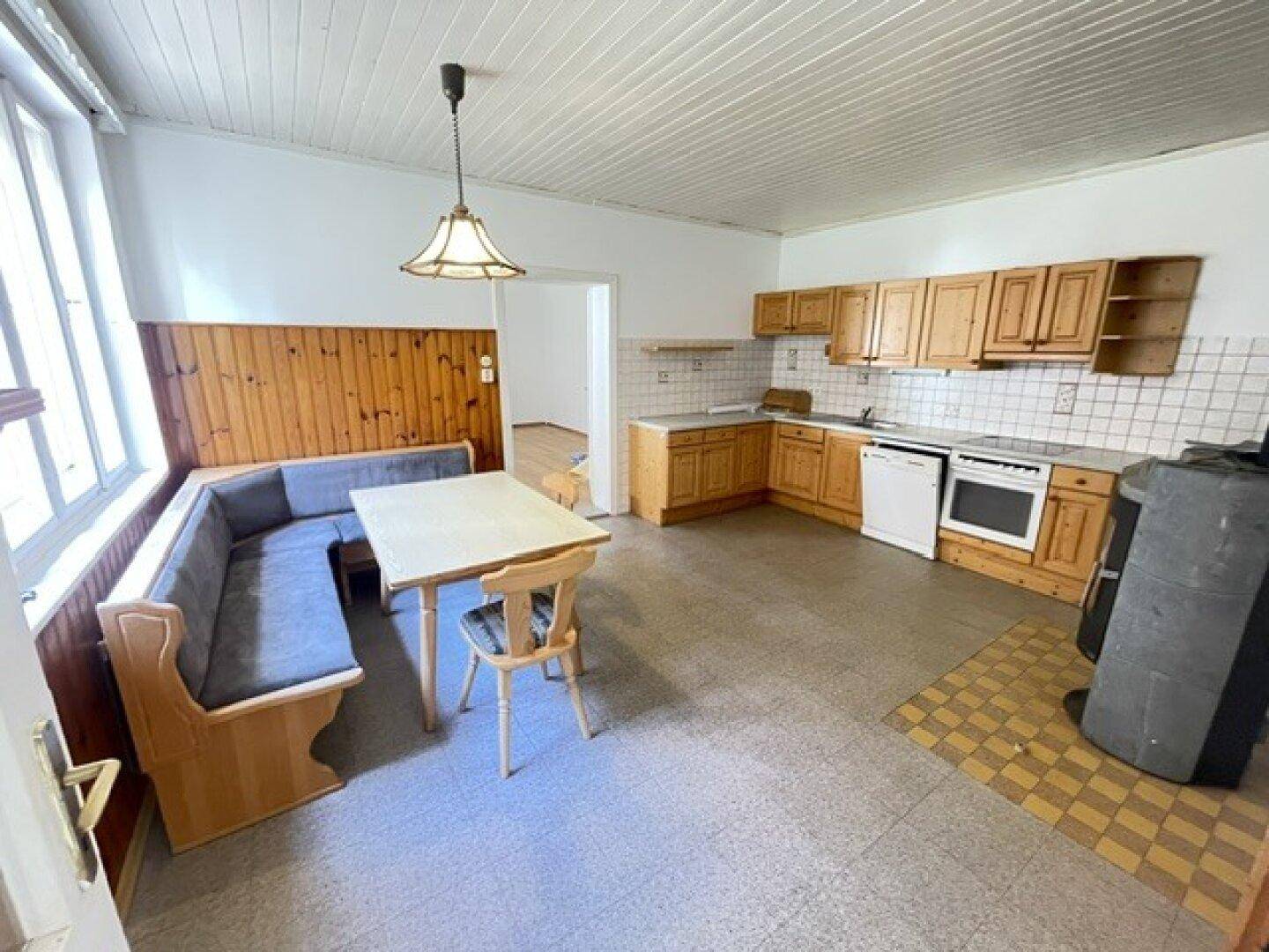 Geräumige Wohnküche im Landhausstil mit Holzeinbauten, Essbereich und einem Holzofen.