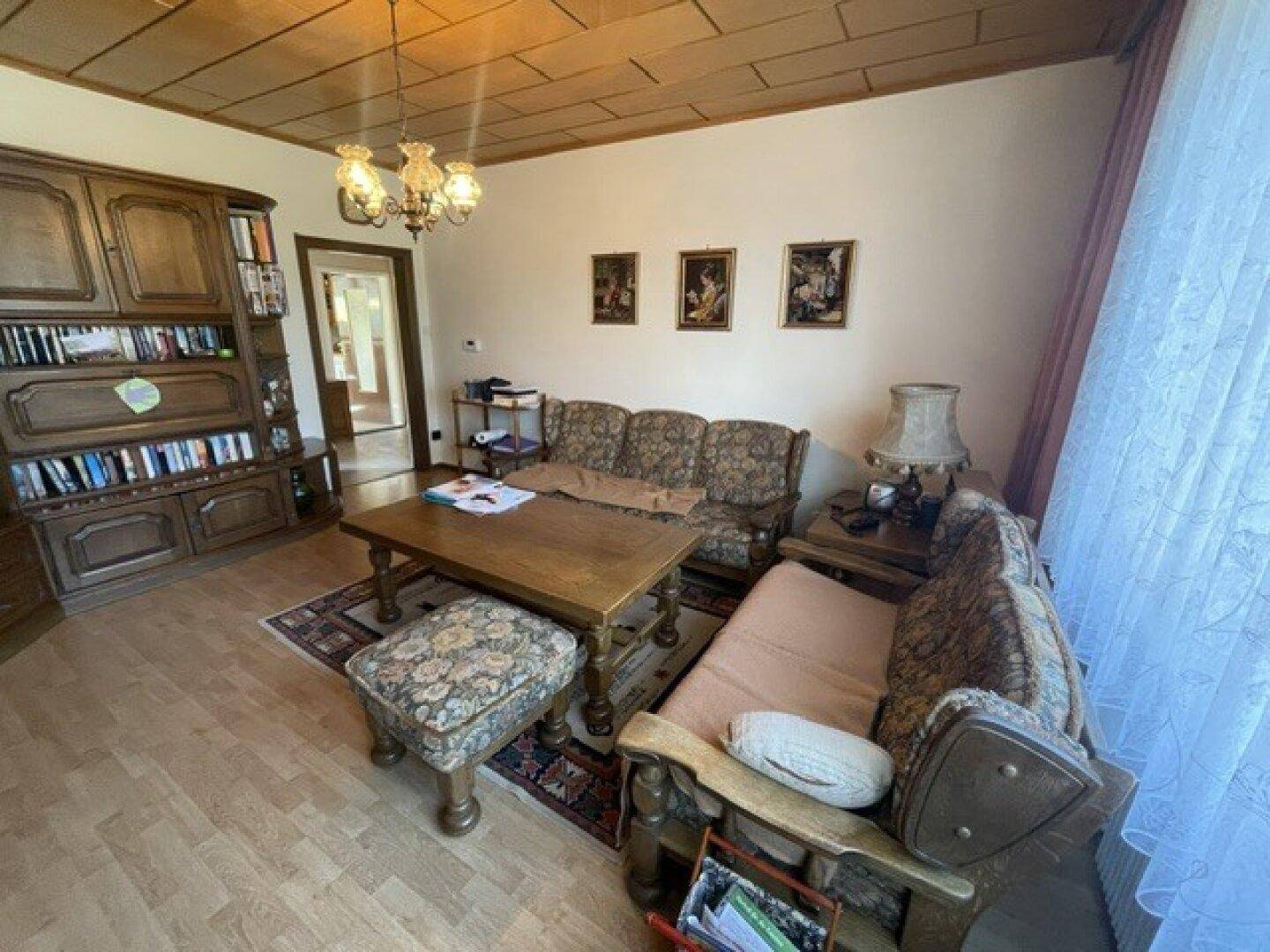 Traditionell eingerichtetes Wohnzimmer mit bequemen Sofas, Holztisch und dekorativer Deckenleuchte.