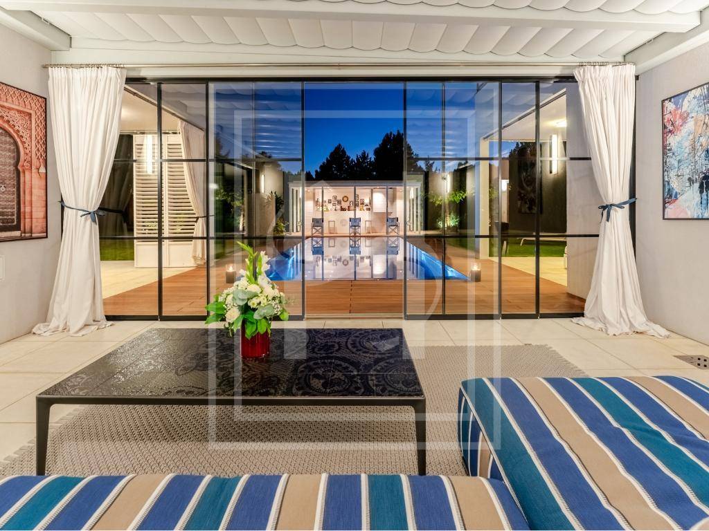 Gemütlicher Wohnbereich mit großen Glasfronten, die den Blick auf den beleuchteten Pool bei Nacht freigeben.