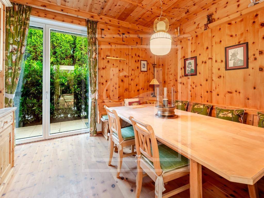 Traditionelles Esszimmer im alpinen Stil mit Holztäfelung, langem Holztisch und gemütlichen Sitzbänken.