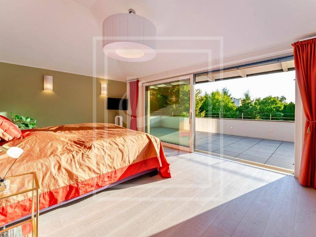 Helles Schlafzimmer mit großem Bett, Holzboden und direktem Zugang zu einer weitläufigen Terrasse.
